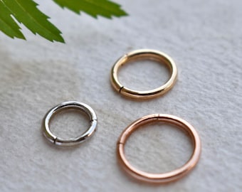 May include: Three seamless hoop earrings in different sizes and colours: gold, rose gold, and silver. The hoops are made of metal and have a smooth finish.