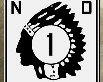Könnte beinhalten: Ein schwarz-weißes Schild mit den Buchstaben "ND" auf beiden Seiten eines Kreises, der die Zahl "1" enthält. Hinter dem Kreis befindet sich ein schwarz-weißes Bild eines indigenen Kopfes mit Kopfbedeckung.