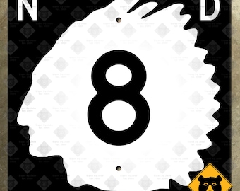 Könnte beinhalten: Ein weiß-schwarzes Straßenschild des Bundesstaates North Dakota mit einer schwarzen Zahl 8 in einem weißen Kreis. Das Schild hat eine schwarze Silhouette eines indianischen Kopfes auf der linken Seite und eine schwarze Silhouette eines Bärenkopfes auf der rechten Seite.