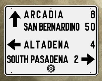 Könnte beinhalten: Weißes Schild mit schwarzem Text und Pfeilen, die die Richtung nach Arcadia (8 Meilen), San Bernardino (50 Meilen), Altadena (4 Meilen) und South Pasadena (2 Meilen) anzeigen. Das Schild enthält auch ein Schwarzweißlogo des Auto Club of Southern California.