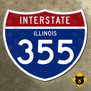 Pode incluir: Uma placa de rodovia interestadual azul e vermelha com texto branco. A placa diz "Interstate Illinois 355".