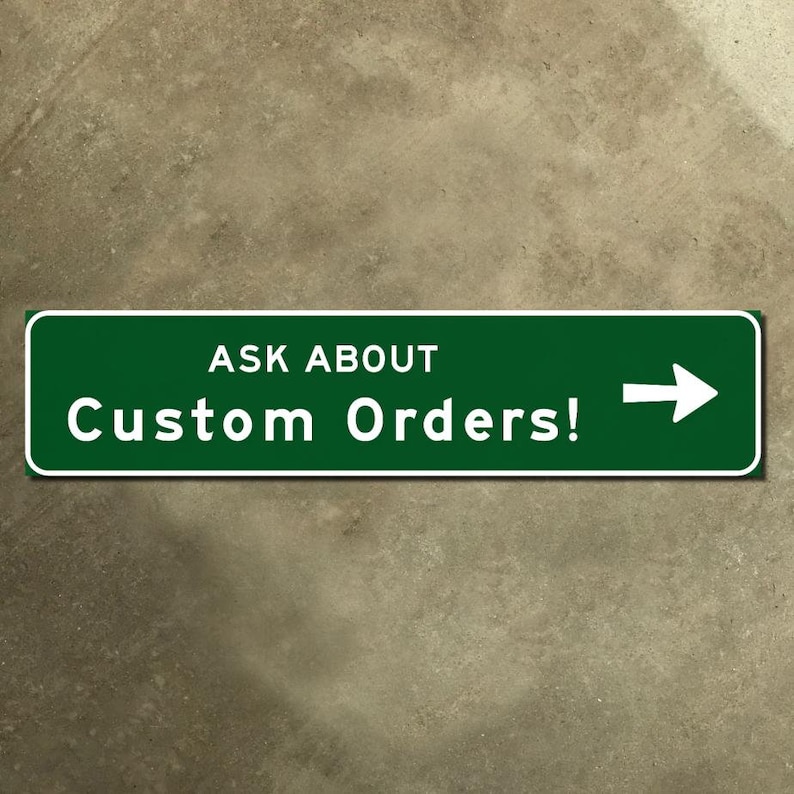May include: A green rectangular sign with white text that reads "ASK ABOUT Custom Orders!" and a white arrow pointing right. The sign has a white border and is set against a textured, neutral-toned background.