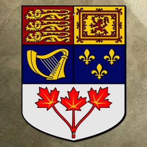 Puede incluir: Un emblema en forma de escudo con un diseño rojo, blanco y azul. El cuadrante superior izquierdo presenta un león dorado sobre fondo rojo. El cuadrante superior derecho presenta un león dorado sobre fondo amarillo. El cuadrante inferior izquierdo presenta un arpa dorada sobre fondo azul. El cuadrante inferior derecho presenta tres flores de lis doradas sobre fondo azul. La parte inferior del escudo presenta tres hojas de arce rojas sobre fondo blanco.