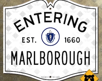 May include: A white sign with a black border, featuring the words "ENTERING MARLBOROUGH" in bold letters. It includes the text "EST. 1660" and a circular emblem. A yellow bear sign is in the lower right corner.