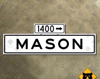 Op de afbeelding: Een wit straatnaambord met zwarte tekst die "MASON" aangeeft en een kleiner wit bord erboven met zwarte tekst die "1400 ->" aangeeft.