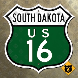 May include: A green and white US highway sign with the text "SOUTH DAKOTA" and "US 16" on it.