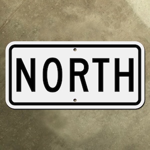 Może przedstawiać: Biały prostokątny znak z czarną ramką i czarnym tekstem, który brzmi "NORTH".
