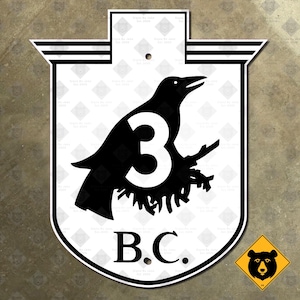 May include: A black and white sign featuring a raven perched on a branch with the number 3. The letters "B.C." are below the raven. The sign has a shield shape with a decorative top.