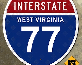 May include: A shield-shaped Interstate 77 road sign with a red top banner reading INTERSTATE in white, a blue main section with the text WEST VIRGINIA and the number 77 in white, and a small yellow diamond logo featuring a black bear head.
