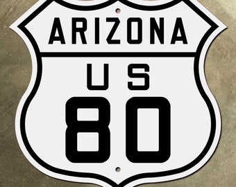 Op de afbeelding: Wit en zwart US Route 80 bord met de tekst "ARIZONA" bovenaan en het nummer "80" in grote zwarte letters.