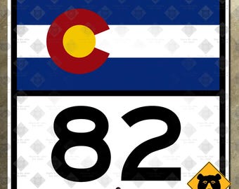 Könnte beinhalten: Ein rechteckiges Schild mit dem Design der Staatsflagge von Colorado in Blau, Weiß, Rot und Gelb. Unter der Flagge ist die Zahl "82" in großer, fetter schwarzer Schrift dargestellt. Ein gelbes Bärenwarnschild befindet sich in der unteren rechten Ecke.