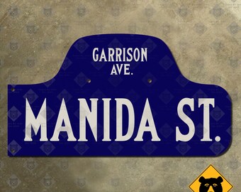 May include: A blue and white street sign with the text "Garrison Ave." and "Manida St."