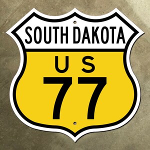 May include: A yellow and white road sign with black text. The sign reads "South Dakota" and "US 77".