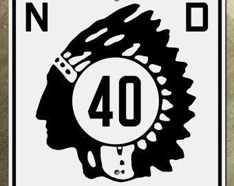 Könnte beinhalten: Schwarzweißes Schild mit einem Profil eines indianischen Kopfes, der eine Kopfbedeckung trägt. Das Schild hat die Buchstaben "N" und "D" in den oberen Ecken und die Zahl "40" in einem Kreis in der Mitte.