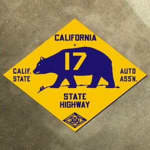 May include: A yellow diamond-shaped sign with a blue bear and the text "CALIFORNIA STATE HIGHWAY 17 AUTO ASS'N."