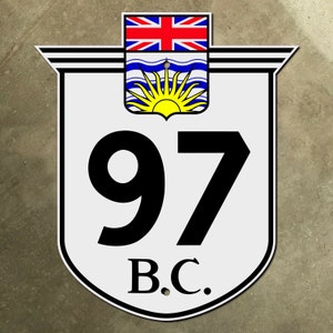 May include: A white shield-shaped sign with black lettering and a blue and yellow Canadian flag. The sign reads "97 B.C."