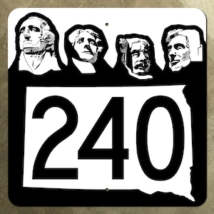 May include: Black and white sign with the number 240 in large white font. The sign features an outline of the state of South Dakota with four faces carved into the top of the sign.