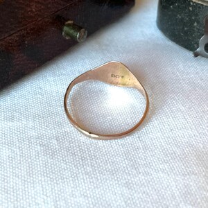 May include: A gold ring with a triangular face and a rounded band. The ring has the letters "SCT" engraved on the face. The ring is set against a white background.