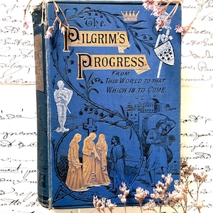 May include: A vintage hardcover book titled "The Pilgrim's Progress" in blue with gold lettering and illustrations. The cover features a knight, a crown, and figures in period clothing. Decorative floral accents are present.