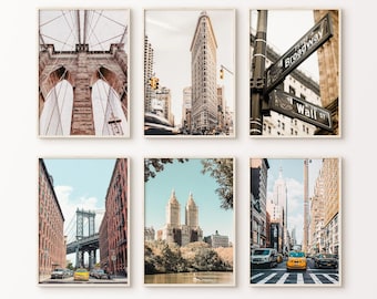 May include: Six framed prints featuring iconic New York City landmarks. Images include the Brooklyn Bridge, the Flatiron Building, street signs for Broadway and Wall Street, the Manhattan Bridge, and Central Park's twin towers.