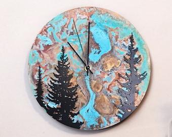 May include: A circular wall clock with a forest silhouette design. The clock face has a blue, brown, and copper marbled effect. Black clock hands show the time. The clock is mounted on a light-coloured wall.