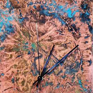 May include: A copper-colored clock face with a blue and green marbled pattern. Black clock hands point to the time.
