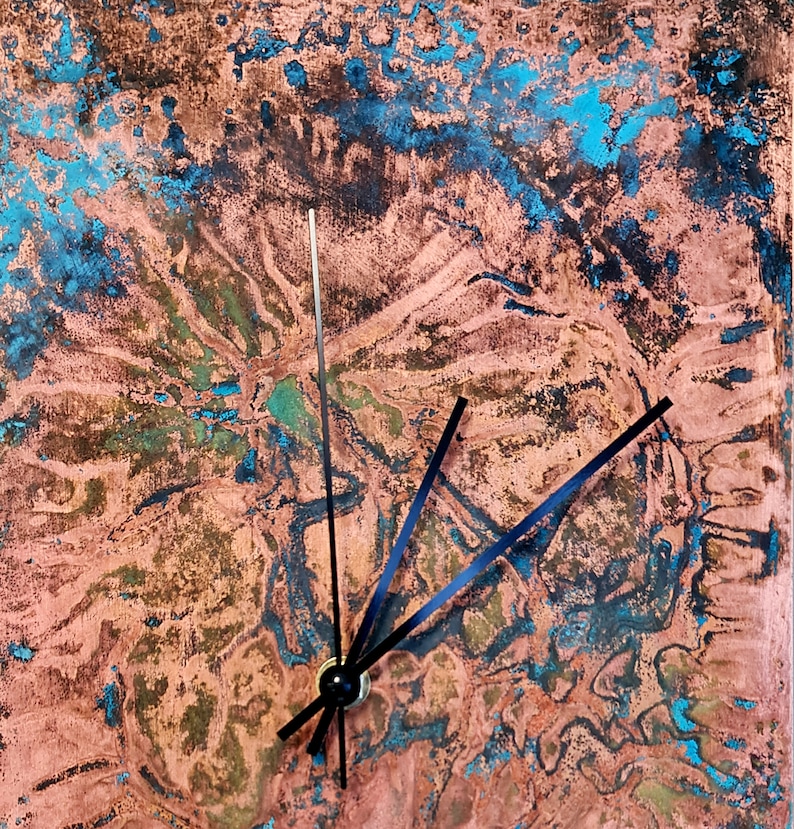 May include: A copper-colored clock face with a blue and green marbled pattern. Black clock hands point to the time.