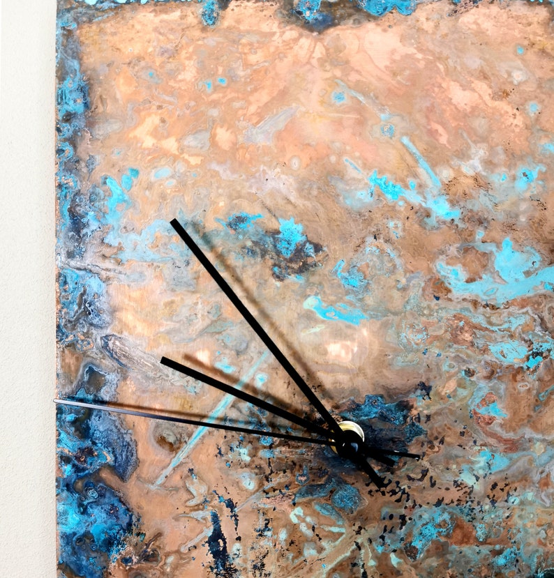 May include: A copper clock face with a blue and brown marbled pattern. The clock has black hands.