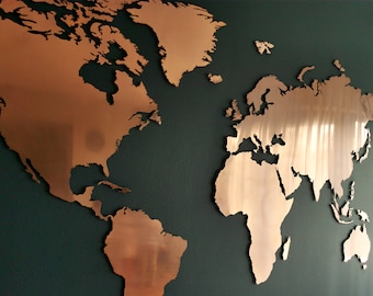 May include: A copper-colored world map wall decor with a raised, three-dimensional design. The map is mounted on a dark green wall.