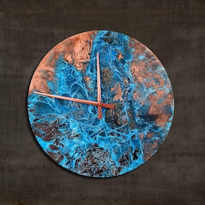 May include: A round clock with a blue and copper abstract design. The clock hands are copper coloured.