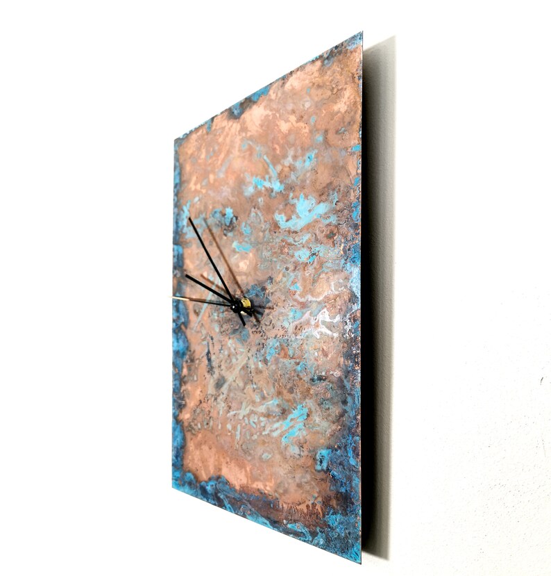 May include: A square copper clock with a blue and brown marbled design. The clock has black hands and a gold center.