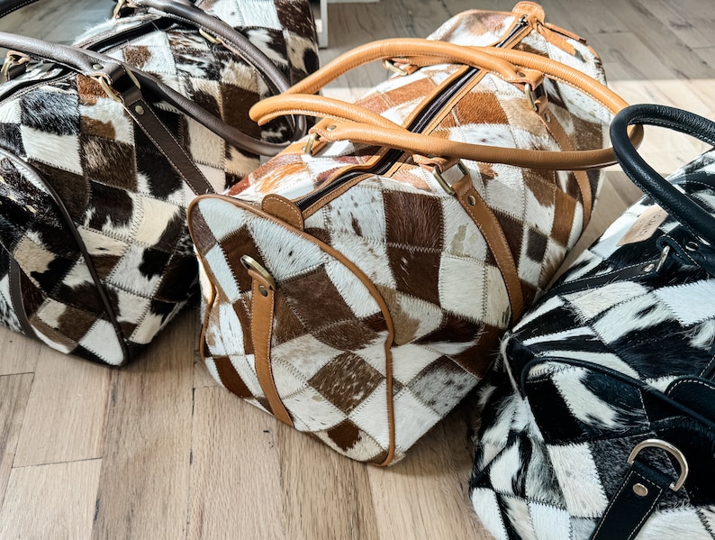 May include: Three brown, black and white patchwork leather travel bags with brown leather handles.