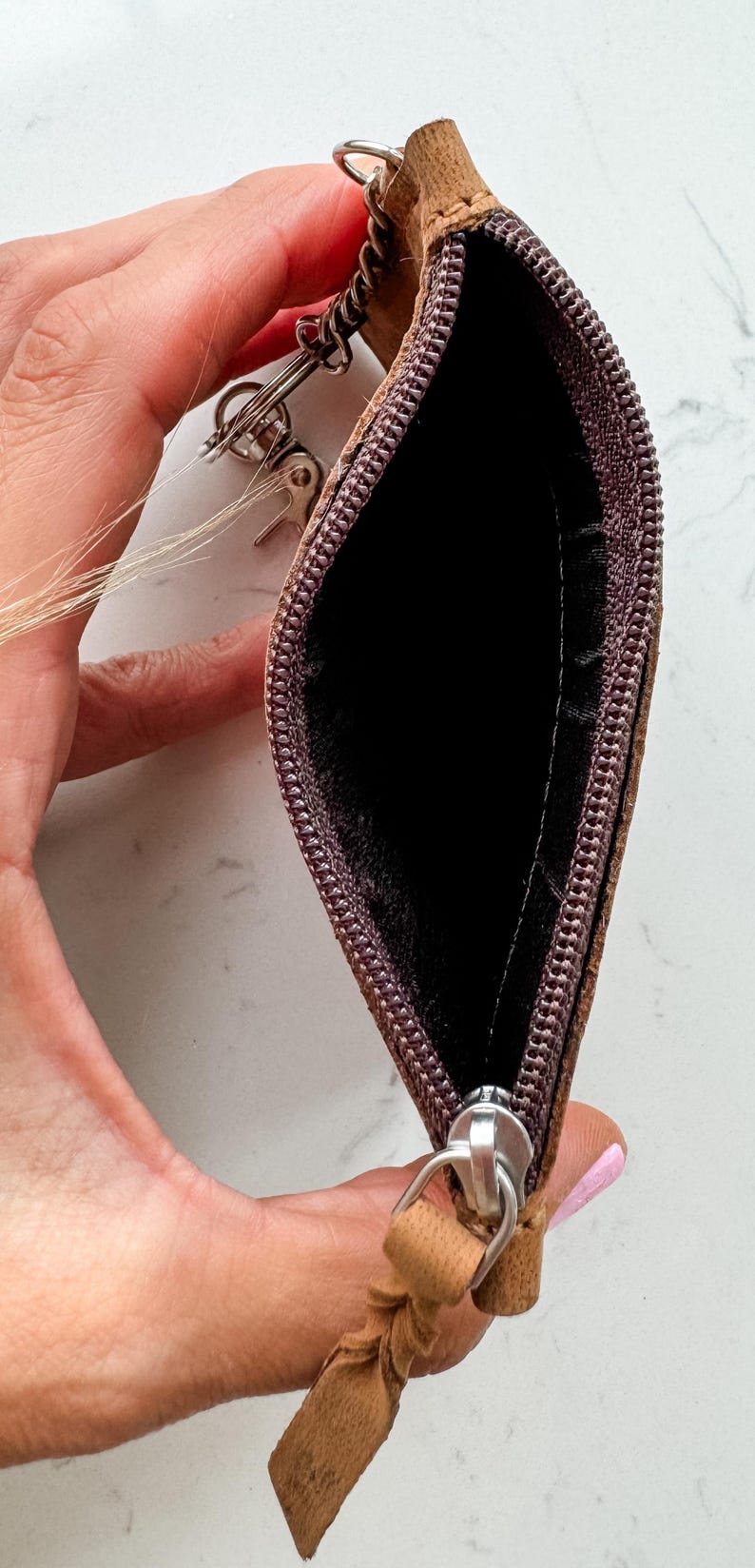 May include: A brown leather key chain with a zippered pouch and a metal key ring. The pouch is open and the zipper pull is visible.