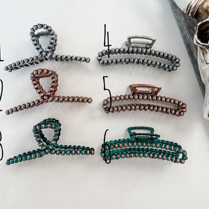 May include: Six different hair clips made of metal and beads. The clips are in various colors, including silver, copper, and teal.