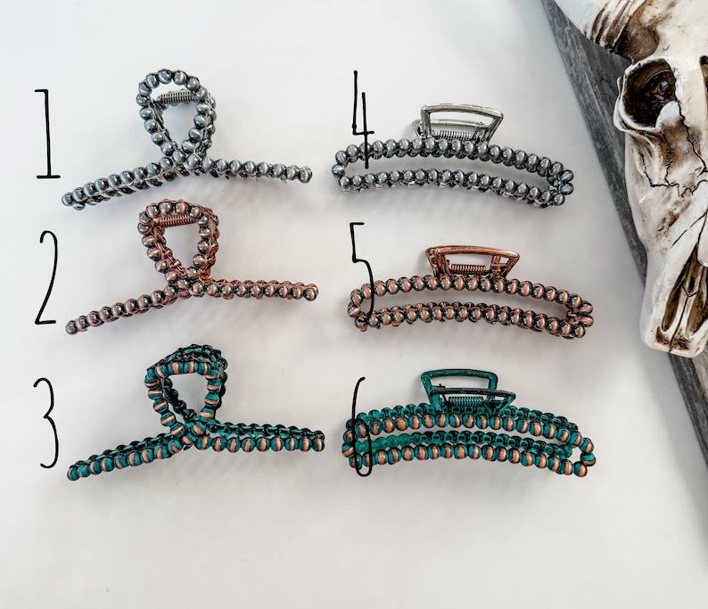 May include: Six different hair clips made of metal and beads. The clips are in various colors, including silver, copper, and teal.