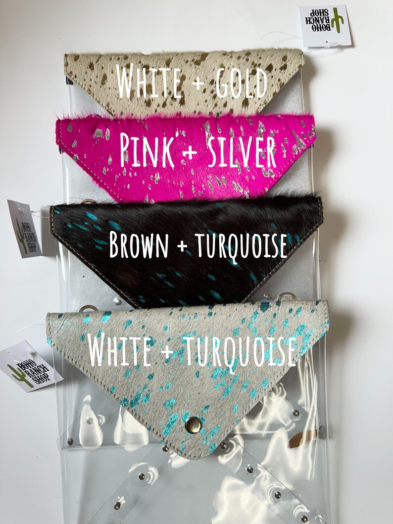 May include: Four triangular cowhide pouches with metallic finishes. The top is white and gold, the second is pink and silver, the third is brown and turquoise, and the bottom is white and turquoise. Each pouch features a snap closure and metal hardware.
