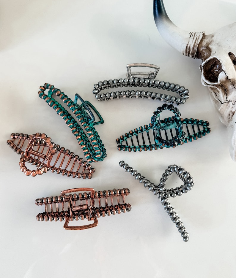 May include: Six hair clips with a beaded design. The clips are in various colors, including silver, copper, and green.