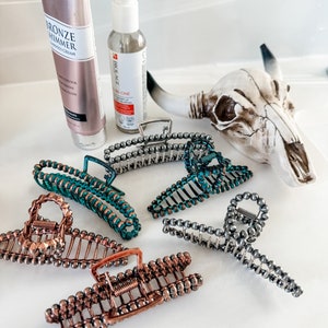 May include: Five hair clips with a beaded design. The clips are in various colors, including silver, copper, and teal.