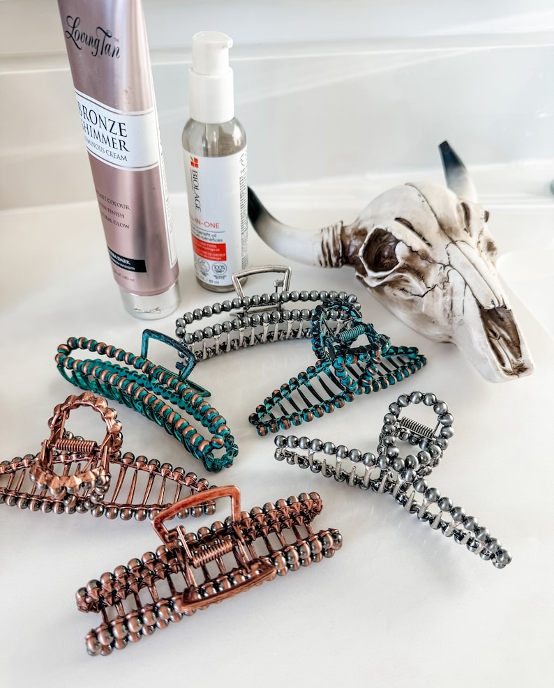 May include: Five hair clips with a beaded design. The clips are in various colors, including silver, copper, and teal.