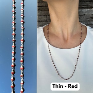 Puede incluir: Un collar de cadena de plata con cuentas rojas. El collar es delgado y tiene un aspecto delicado. El texto "Thin - Red" es visible en la parte inferior de la imagen.
