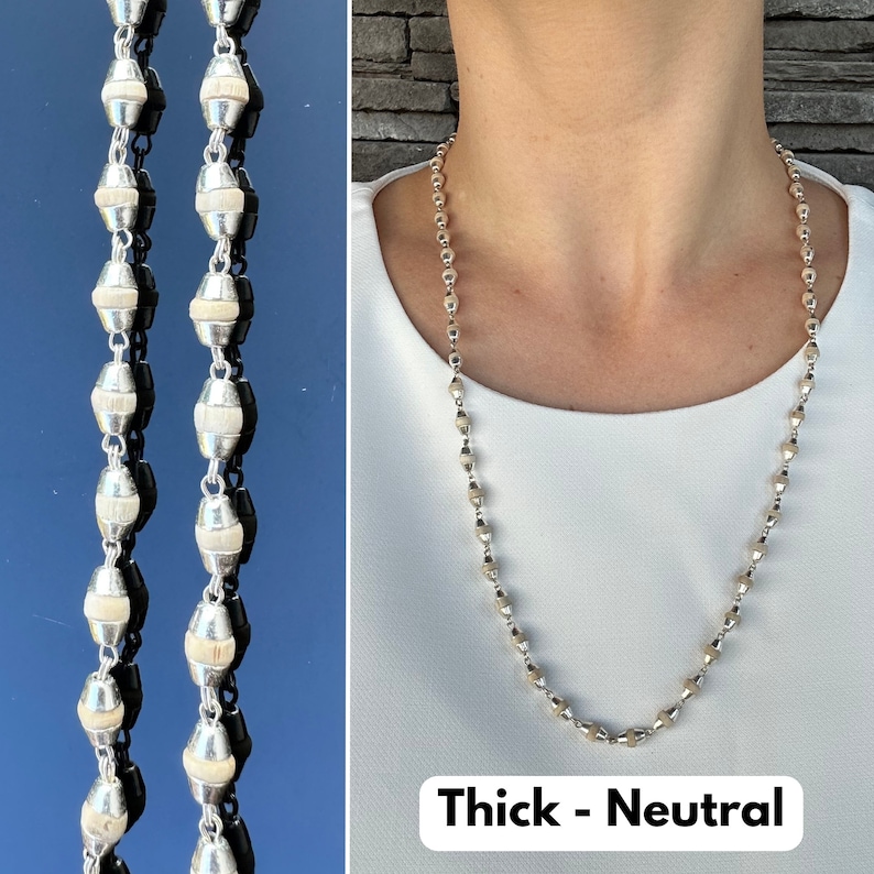 Puede incluir: Un collar de plata con peque&ntilde;as cuentas redondas. El collar es grueso y tiene un color neutro. El texto "Thick - Neutral" est&aacute; impreso debajo del collar.