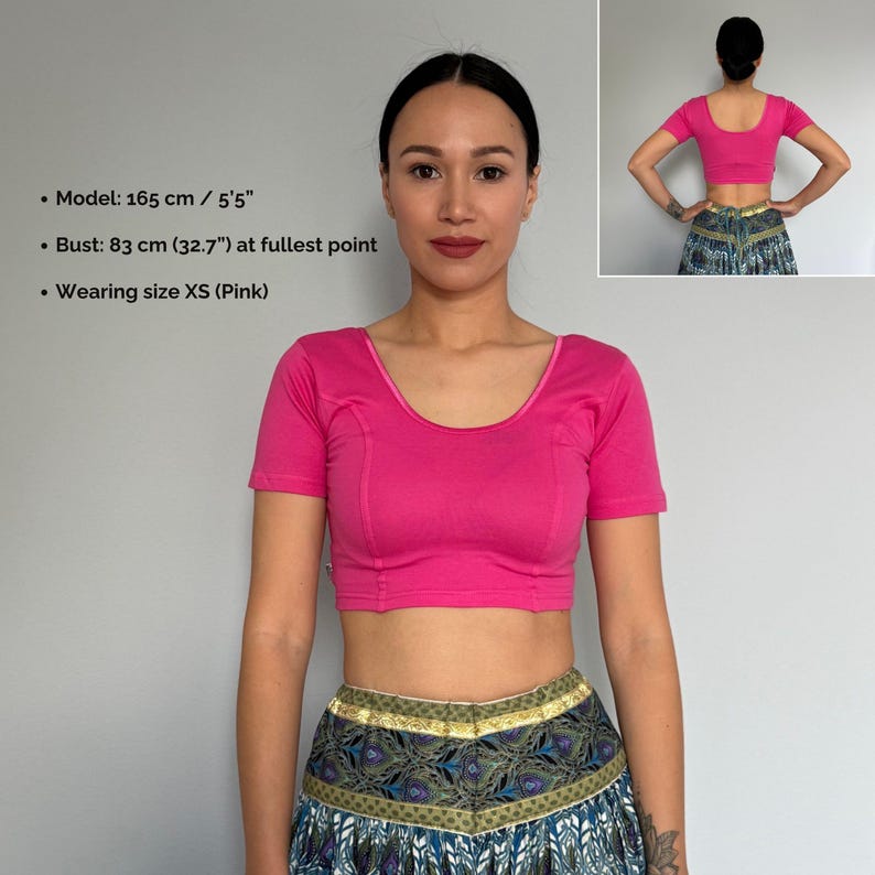 May include: A pink, short-sleeved crop top with a scoop neckline. The top is a solid color and appears to be made of a soft fabric. The model is wearing size XS.