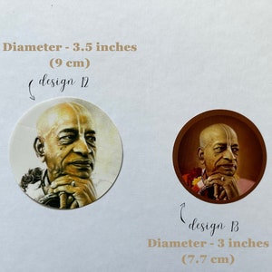Op de afbeelding: Twee ronde stickers met een portret van een man met een geschoren hoofd en een witte streep op zijn voorhoofd. E&eacute;n sticker is 9 cm in diameter, met de aanduiding "design 12". De andere is 7,7 cm in diameter, met de aanduiding "design 13".
