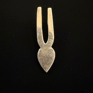 May include: Silver pendant with a heart-shaped design and two prongs at the top.