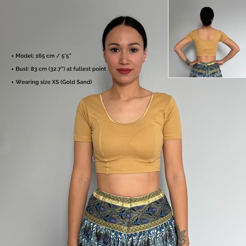 May include: A cropped, short-sleeved top in a gold sand color. The top has a scoop neckline and a fitted silhouette. The model is wearing size XS. The bust measurement is 32.7 inches. The model is 5'5" tall.