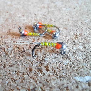 May include: Four fly fishing lures with orange and yellow bodies and silver hooks.