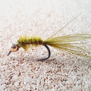 May include: A green and gold fly fishing lure with a feathered tail.