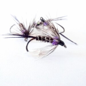 May include: Three purple and black fly fishing lures with white feathers and silver hooks.