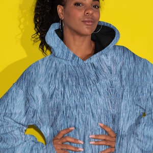 May include: A blue and white oversized hoodie with a brushed denim pattern. The hoodie has a drawstring hood and a kangaroo pocket.