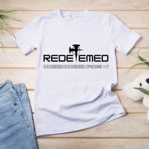 May include: White t-shirt with a black graphic of a hammer and nail with a circle around it. The text "REDEEMED" is below the graphic, and the text "EPHESIANS 1:17" is below that.
